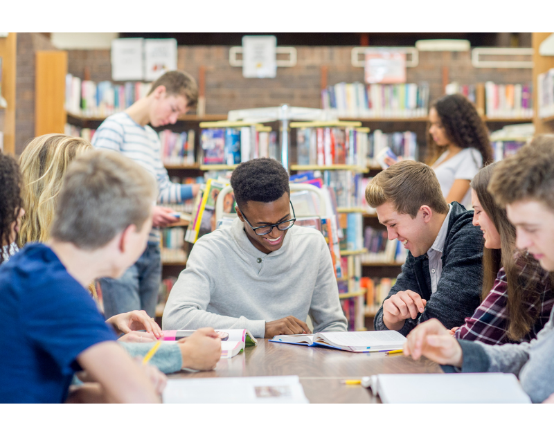 teens reading books Seven teens sitting in a library reading books, two teens in background browsing bookshelves